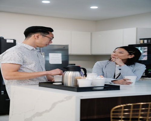 A person making a coffee in a bright office kitchen